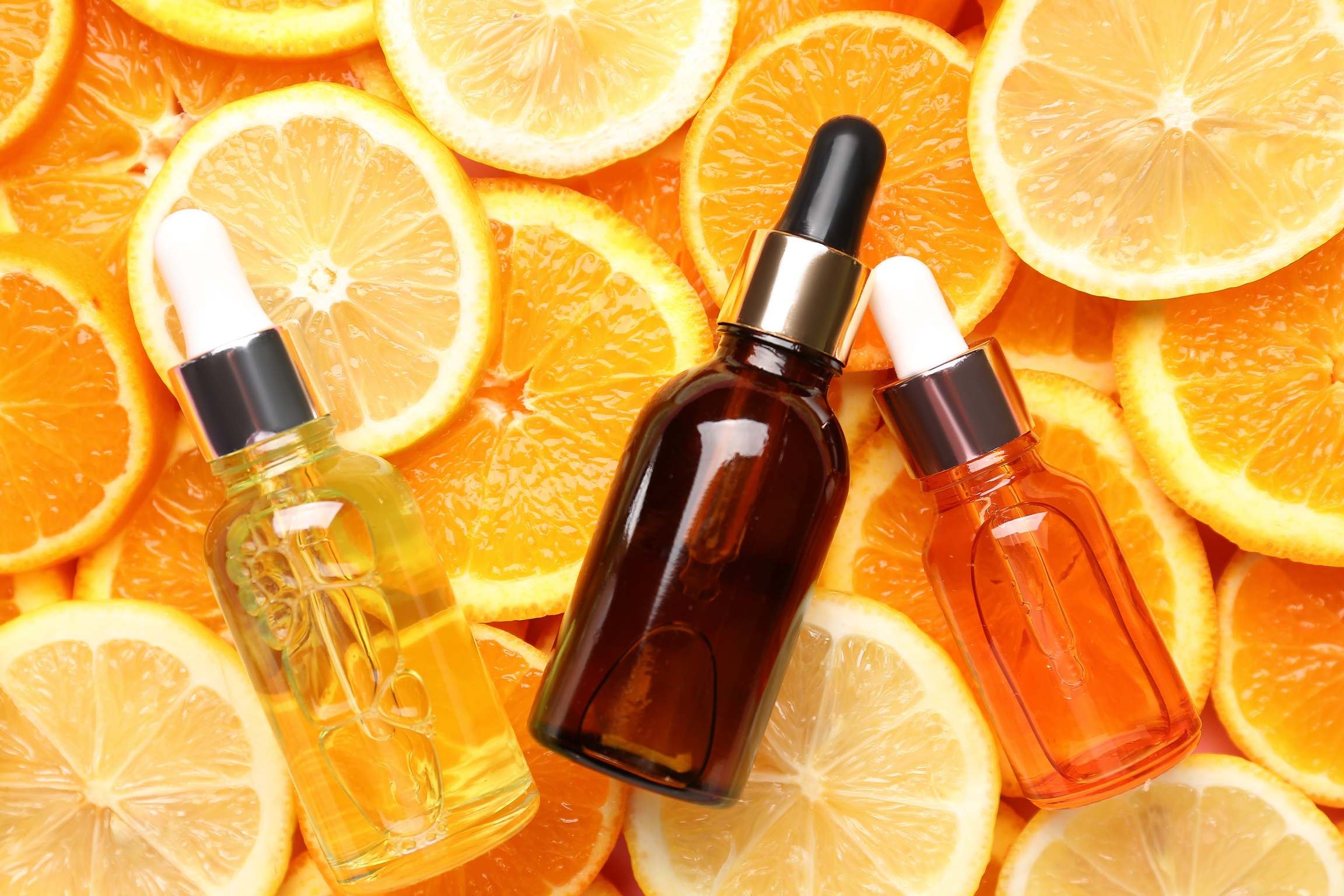 Bottles with Vitamin C Serum on Slices of Citrus Fruits